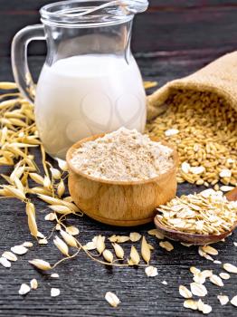 Flour oat in bowl, grain in a bag, oatmeal in a spoon, oaten stalks on the background of dark wooden board