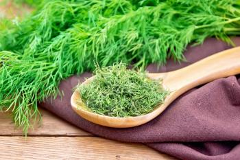Dry dill in a spoon on a napkin, fresh herb on the background of an old wooden board