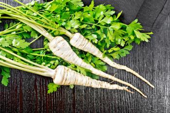 Whole parsley roots with green tops, a napkin on wooden board background from above