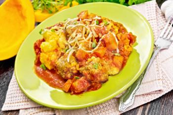 Corn porridge with meatballs, sauce of tomato, garlic and pumpkin, sprinkled with cheese and parsley in a plate on towel against the background of dark wooden board