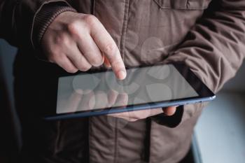 The man uses a tablet PC. Modern gadget in hand.