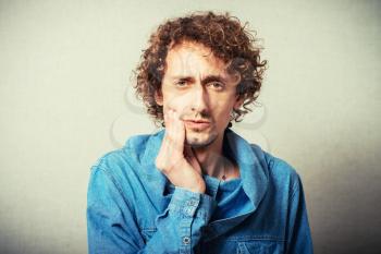 curly-haired man showing a toothache