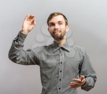 Young handsome man raised one hand. Gesture. On a gray background