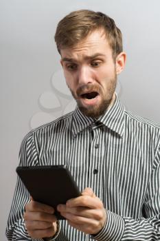 shocked man holding tablet pc and screaming. studio shot over dark background
