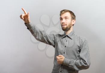 Closeup portrait of happy young smiling man with beard pointing to space at left with index finger isolated on white background. Positive human emotion signs symbol, facial expression feelings