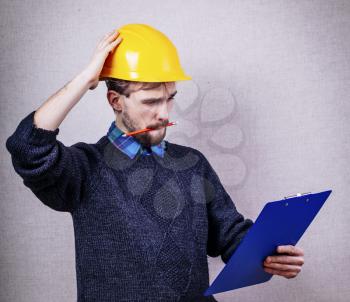 Young builder in helmet thought about project