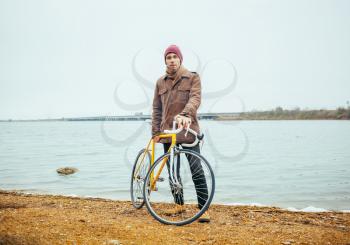 a young man with a bicycle near the shore