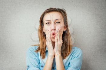 woman grimace hands on cheeks. isolated on gray background