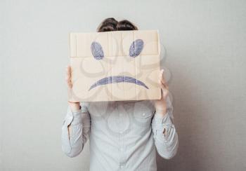 young man holding a picture of a sad smiley