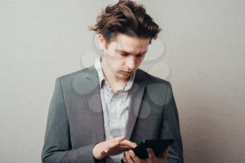 Thinking young man with calculator on grey