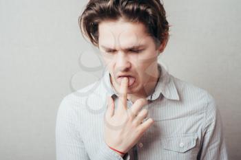 Close Up portrait of young man, annoyed, frustrated fed up sticking fingers in ??? throat.