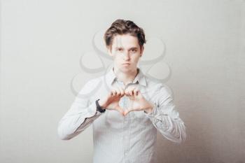 attractive young man makes the heart using fingers