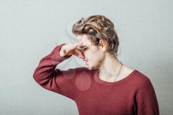 The man closed his nose on the stinky smell. On a gray background.