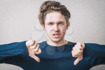 young businessman shows thumb down gesture, unhappy, sad face, studio shoot