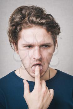 Man thinks with finger in his mouth. Gray background