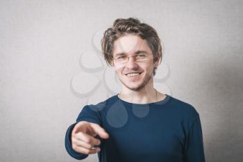 A man shows his index finger forward. Gray background.