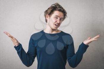 Man angry, shouts, lifting his hands up. Gray background