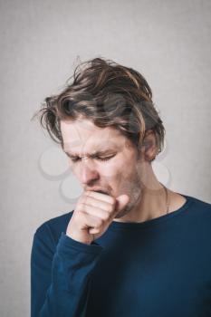 A man coughing into his fist. Gray background
