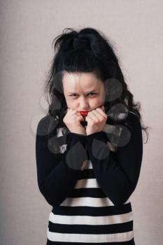 Woman thinks with his fists near the face. Gray background.