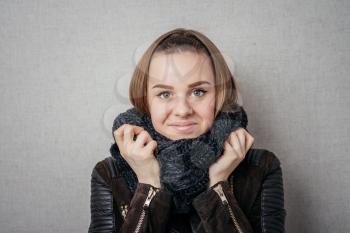 It is so cold. Frozen young women covering face with turtleneck while standing against grey background