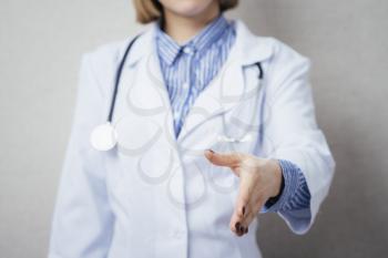 Friendly woman doctor extends his hand