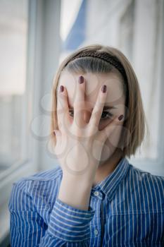 young attractive woman suffering depression and stress standing alone in pain and grief against window feeling sad and desperate at home with studio backlight
