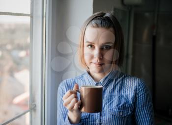 woman drinking coffee in the morning sitting by the window.