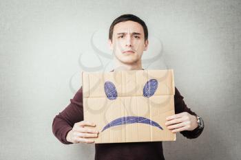 man, holding a picture of a sad smiley