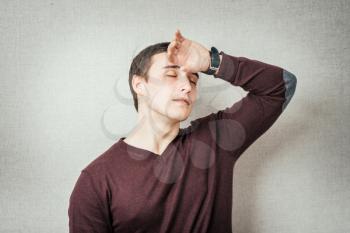 Closeup portrait sad depressed stressed, alone disappointed gloomy young man having headache, regrets, many thoughts isolated orange background. Human emotion facial expression feeling body language