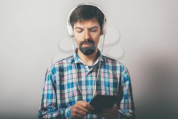 bearded hipster listening to music on headphones with the phone