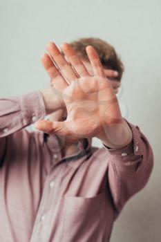 man covers his face with his hand and showing stop