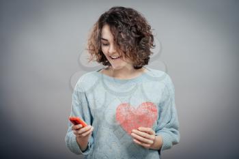 Beauty woman using and reading a smart phone holding red heart isolated 