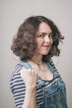 happy girl with fists, dressed in overalls