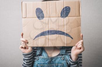 Young woman standing with a cardboard on his head with sad face