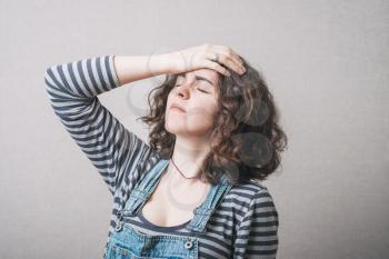 A woman going through a hand on his head. On a gray background.