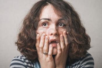 Close-up portrait of surprised beautiful girl holding her head in amazement 