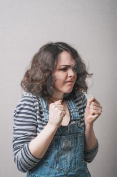 angry woman threatening the fist over grey background