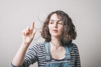 A beautiful young adult woman touching in the air with one finger