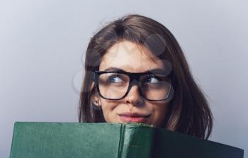 Young beautiful Girl with glasses reading a  big green book
