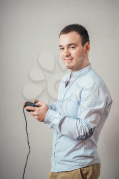 Happy young man in winning pose wearing shirt holding video game joystick.