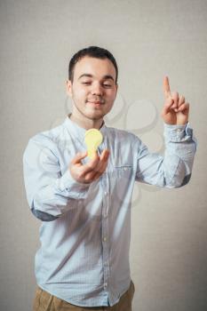 man close-up on a gray background holding a light bulb sticker