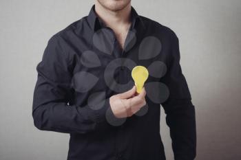 man close-up on a gray background holding a light bulb sticker