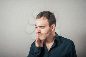 Man shows that a toothache. On a gray background.