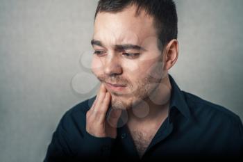 Man shows that a toothache. On a gray background.