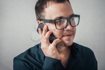 The man with glasses talking on the phone. On a gray background.