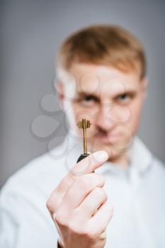 Man wearing a  shirt looking happy holding a rusty key. 