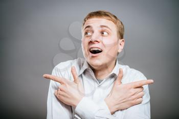 laughing young businessman in suit pointing at something different directions and screaming. isolated 