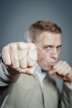 Closeup portrait of an angry businessman threatening with his fist on white background