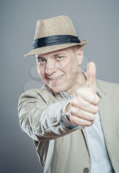 Happy businessman in hat thumbs up sign on gray background