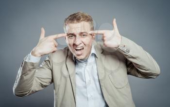 Closeup portrait of angry man gesturing with his finger against his temple, are you crazy?